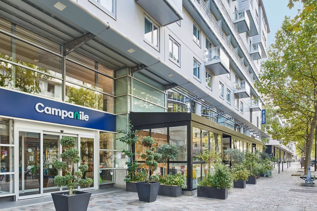Campanile hotel entrance with a glass canopy and planters along the pavement.