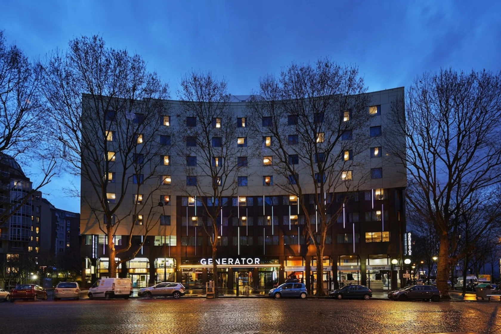 Exterior of Generator Paris hostel at dusk, showing the illuminated entrance and building facade.