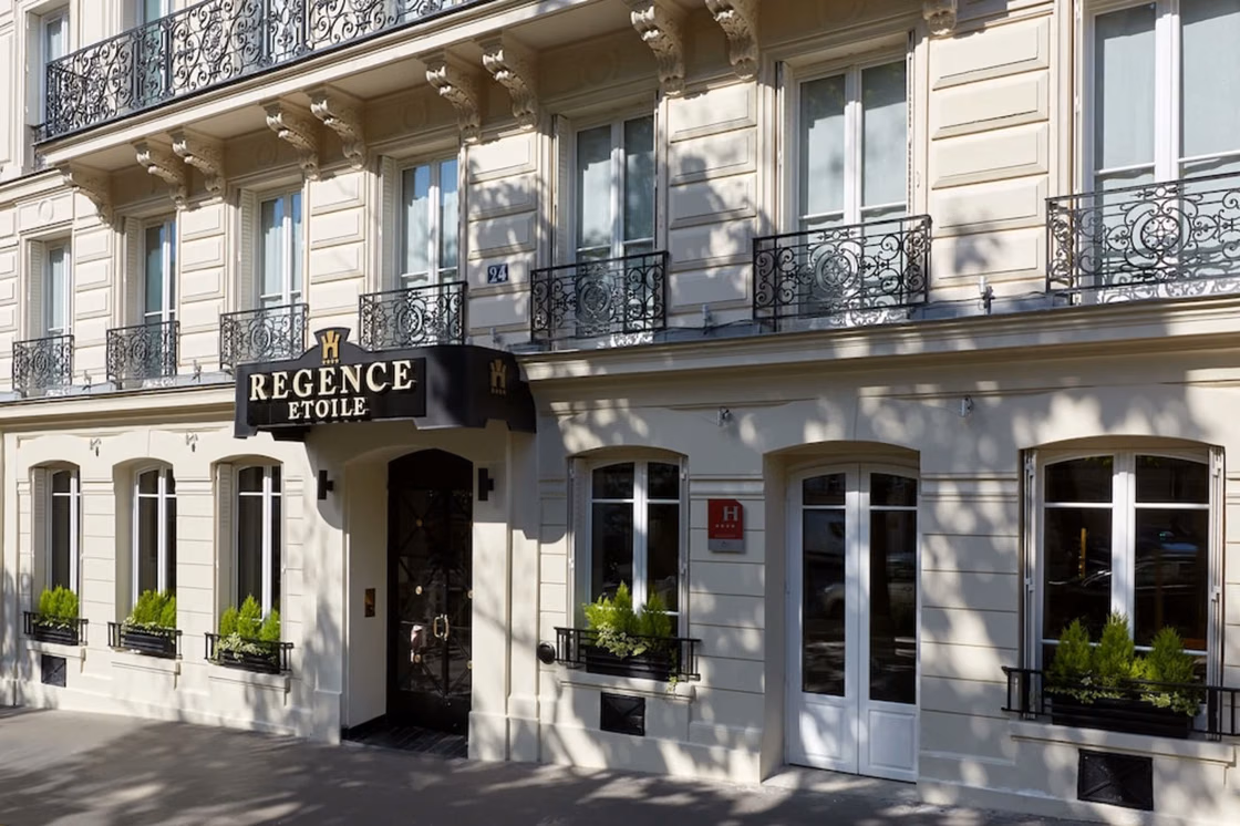 Entrance and facade of Hotel Regence Etoile with wrought-iron balconies.